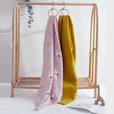 Lady Goose swaddle and mustard blanket hanging side by side on wooden nursery rack